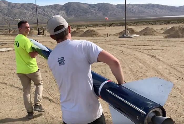 Two of the team members carry the rocket to the launch pad