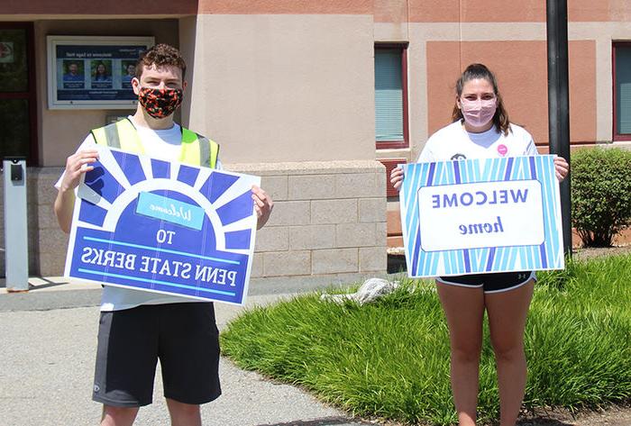 Orientation Leaders hold welcoming signs for incoming students.