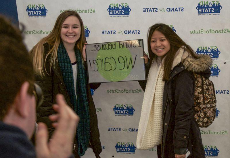 Two students posing with a sign 