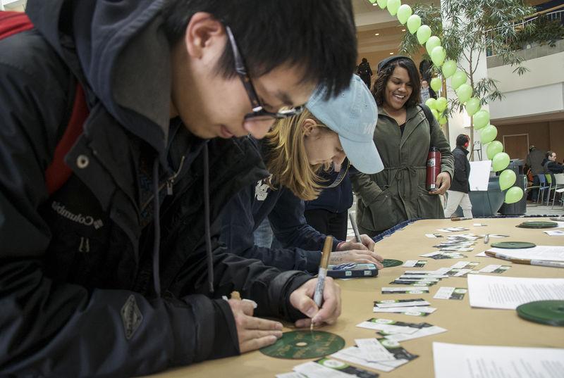 Students writing down messages on green CDs
