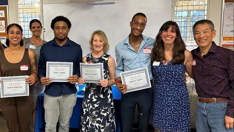 Seven people pose for a photo holding certificates