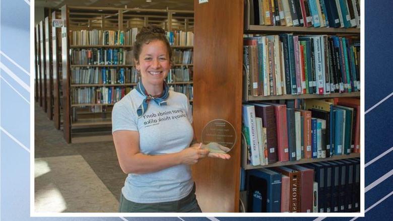 Person holding award in front of bookshelves