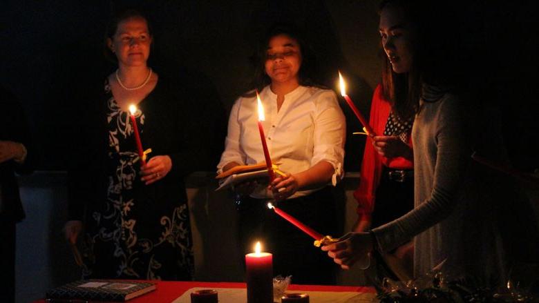 Students light a candle during the induction ceremony for Sigma Delta Pi