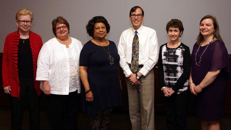 group of five women and one man standing in a row after being honored at a ceremony