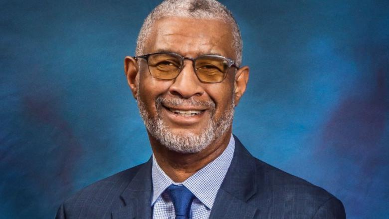 A headshot of Penn State Berks Chancellor George Grant Jr. wearing a blue suit against a blue background.