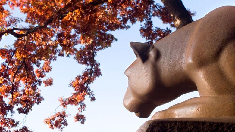 Nittany Lion Shrine with red fall leaves overhead.