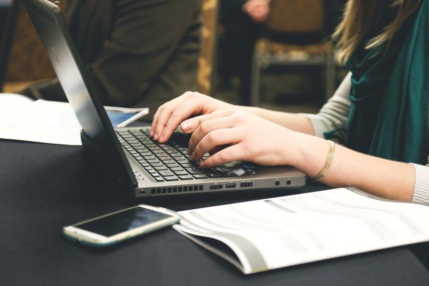 A close-up photo of a woman typing on a computer