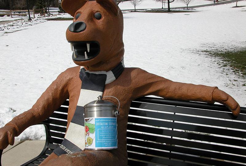 The Nittany Lion statue with a compost container.