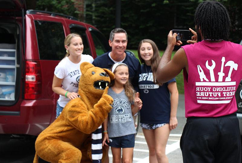 An orientation leader takes a family photo of a first year.