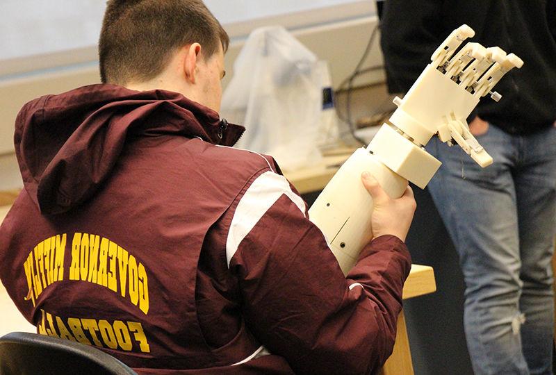 A local high schooler examines a prosthetic arm that was designed by Berks engineering students