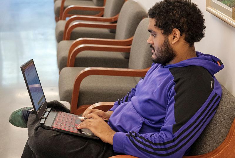 a student works on his laptop in a study space in Gaige