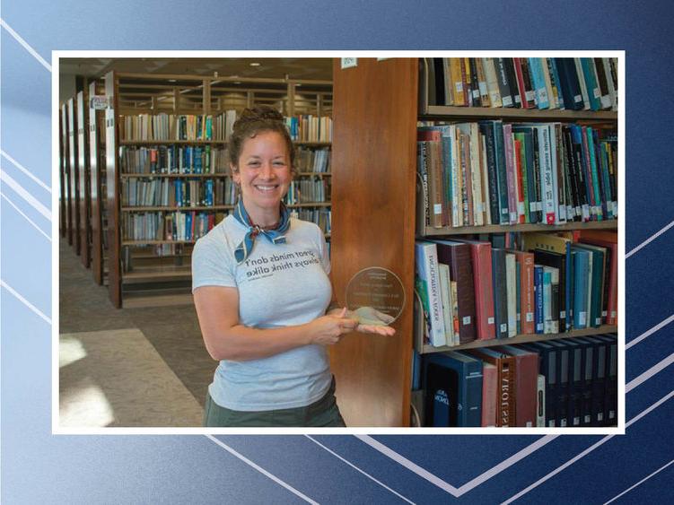 Person holding award in front of bookshelves
