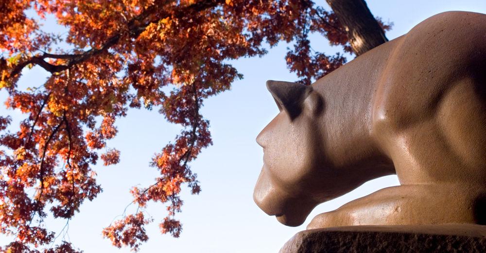 Nittany Lion Shrine with red fall leaves overhead.