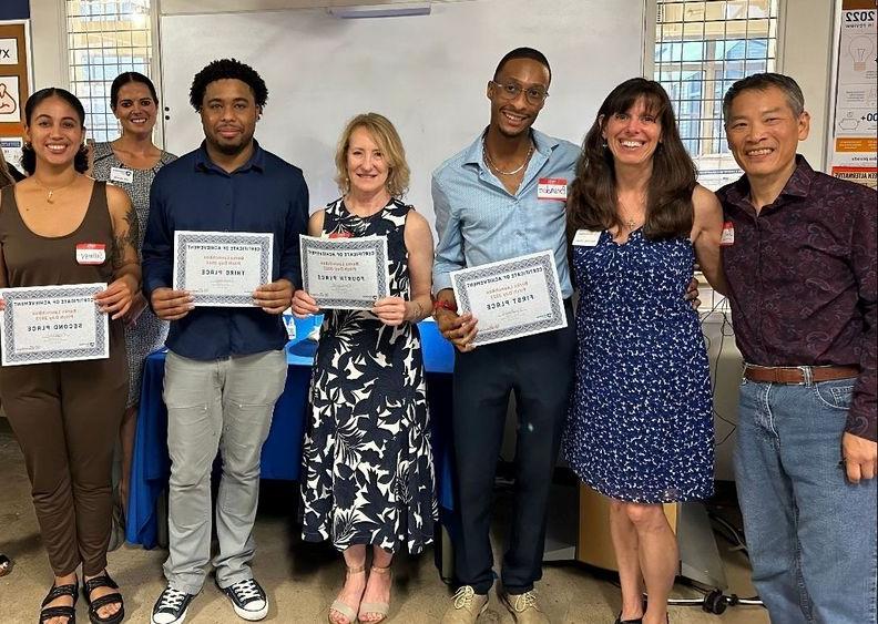 Seven people pose for a photo holding certificates